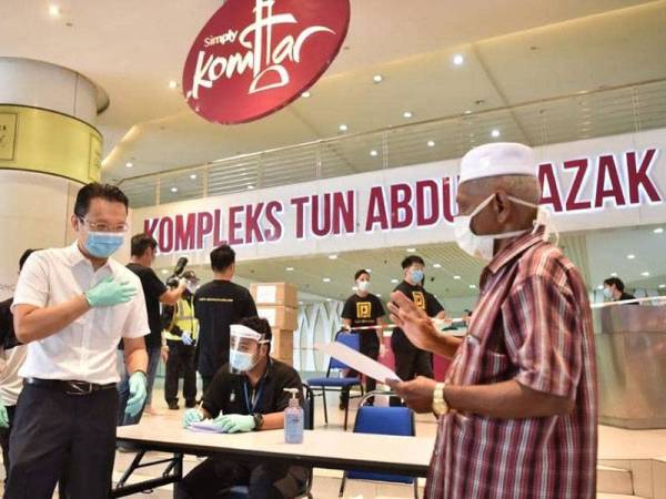 Soon Hin (kiri) menyampaikan bantuan kepada penarik beca di Komtar.