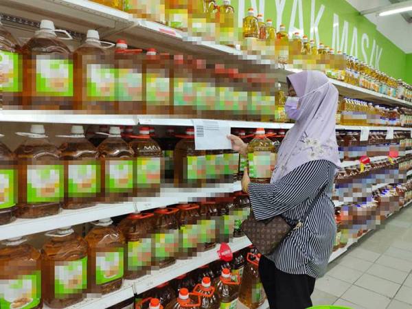 Pelanggan sedang membanding harga minyak bersaiz 5kg di sebuah kedai runcit di Shah Alam, Selangor.