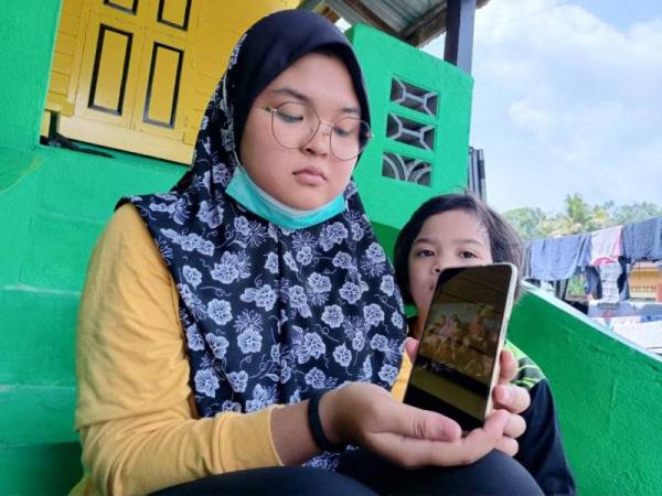 Nurallesyah menunjukkan gambar kenangan mereka tujuh beradik bersama arwah ibu yang dirakam pada sambutan Aidilfitri, tahun lalu.