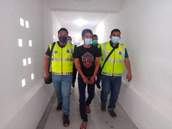 Mohamad Aidil Ikwan (tengah) dikawal polis keluar dari lokap menuju ke Mahkamah Sesyen Kota Bharu pada Rabu.