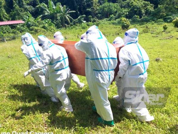 Anggota JBPM Kelantan yang lengkap memakai PPE mengusung keranda jenazah mangsa Covid-19 untuk dikebumikan.