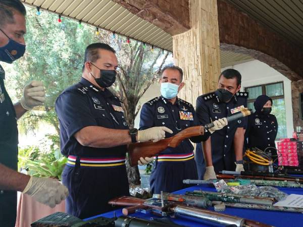 Abdul Majid (tengah) melihat sebahagian senapang tiruan yang dirampas dalam serbuan yang dilakukan pada Khamis.