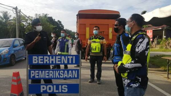 Mohd Adli (kiri) berkata sesuatu kepada anggota polis yang melakukan persiapan sekatan jalan raya susulan pelaksanaan PKPD di Kampung Tajin bermula 12 hingga 25 Jun nanti.