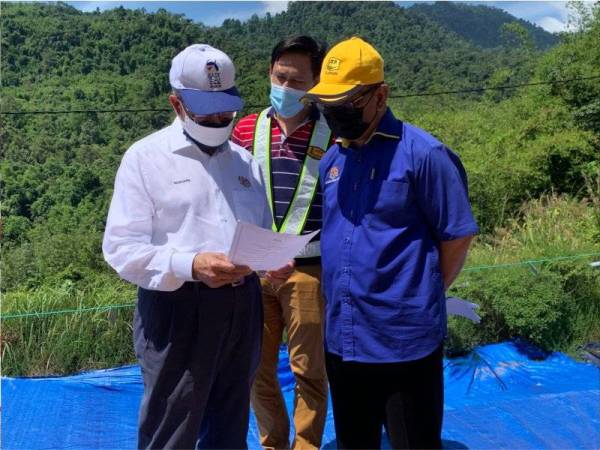 Mustapa (kiri) mendengar taklimat mengenai perkembangan cerun tersebut.