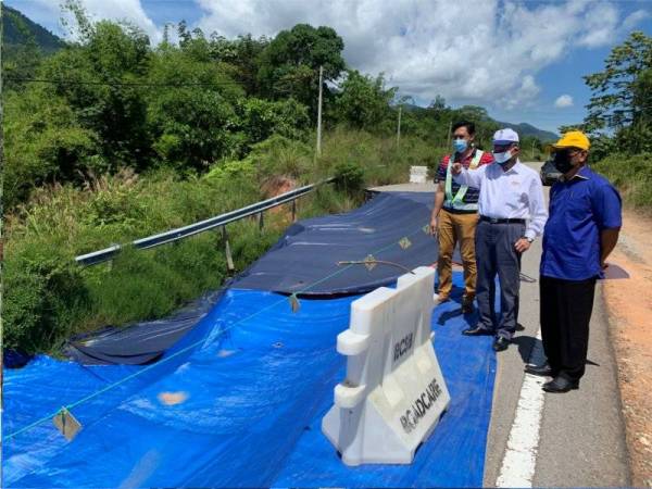 Mustapa (tengah) ketika meninjau keadaan cerun di laluan utama yang runtuh pada Sabtu.
