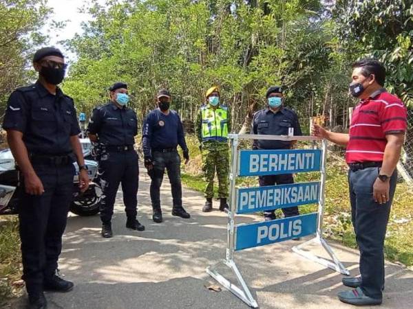 Noor Azmi (kanan) ketika meninjau keadaan sekitar kampung itu pada Ahad. 