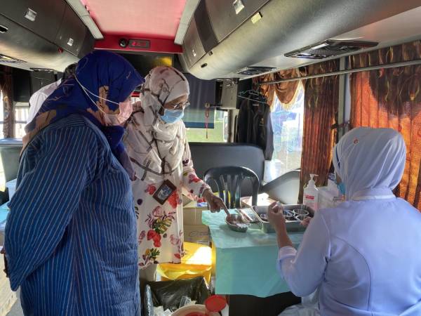 Pegawai Kesihatan Daerah Muar Dr Noorhaidah Ujang (tengah) memberikan penerangan kepada ADUN Sungai Balang Zaiton Ismail (kiri) berkenaan perjalanan Pusat Pengambilan Vaksin (PPV) Bergerak di Kompleks Penghulu Sungai Balang, di sini. -Foto Bernama