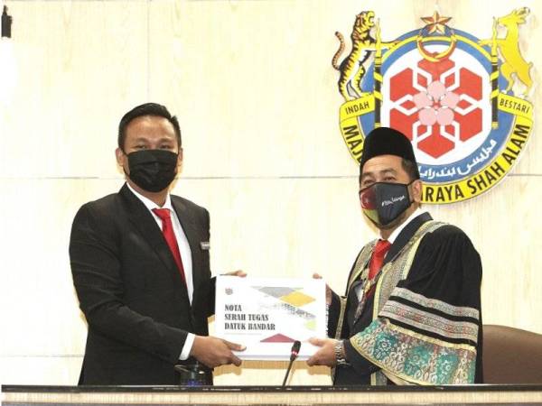 Zamani Ahmad (kanan) menerima nota serah tugas Datuk Bandar daripada Mohd Rashidi di Wisma MBSA di Shah Alam pada Selasa.