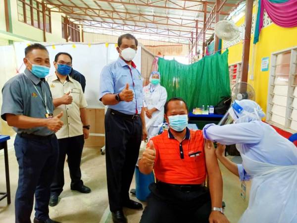 Nik Raisnan (dua dari kiri) memberikan sokongan kepada penduduk yang menerima suntikan vaksin Covid-19 di PPV Bergerak peringkat Jeli di Sekolah Menengah Ugama Ad-Diniah, Batu Melintang pada Selasa.