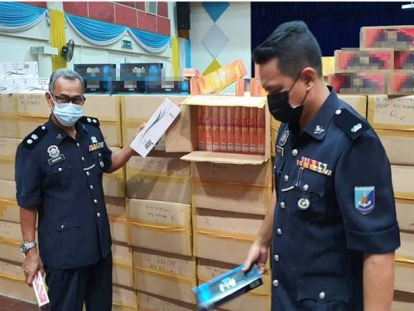 Shoppri (kiri) bersama pegawainya menunjukkan kotak rokok seludup yang dirampas.