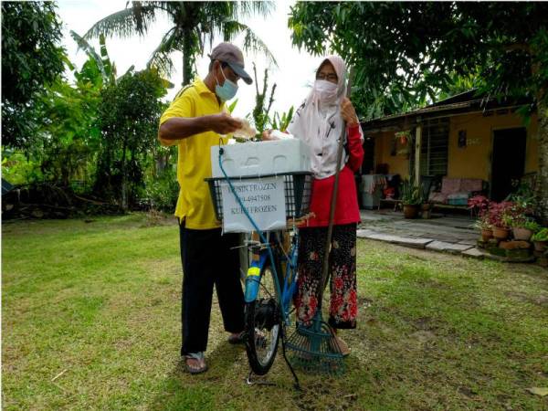 Husin (kiri) bertemu pelanggan yang ingin membeli kuih sejuk beku di sekitar Kampung Tengku Hussein Hujong, Manjoi pada Jumaat. - Foto Bernama