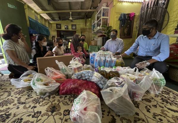 Nor Aziah (tengah) yang mempunyai 11 anak menerima bantuan ihsan dan keperluan harian daripada Mas Imran (dua dari kiri) di di Kampung Permatang, Kempas Baru, Johor Bahru pada Sabtu. - Foto Bernama