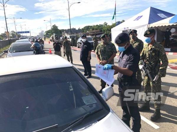 Muhammad Hafizuddeain (empat dari kanan) dan Abdullah memantau petugas yang menjalankan pemeriksaan di SJR Pasir Pekan, Tumpat pada Ahad.