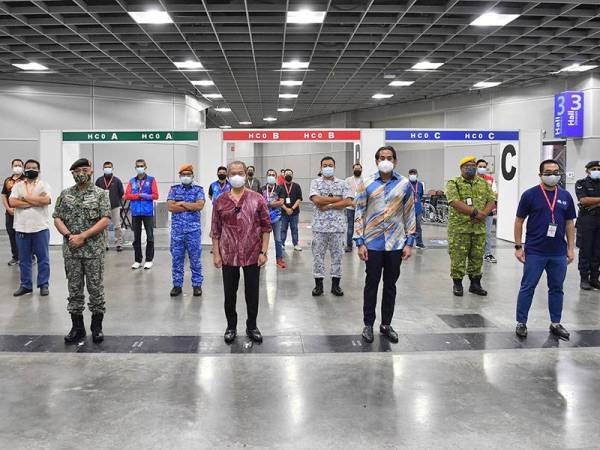 Muhyiddin bergambar bersama wakil agensi sukarelawan ketika membuat lawatan ke Pusat Pemberian Vaksin (PPV) di KLCC hari ini. Turut hadir Khairy Jamaluddin. -Foto Bernama