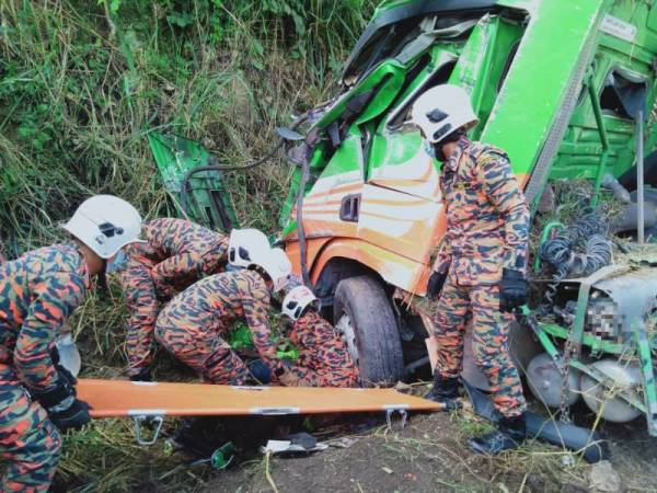 Anggota bomba keluarkan mayat mangsa tersepit di bawah treler yang terbabas di KM44.2 Lebuhraya Kuala Lumpur Karak pada Isnin.