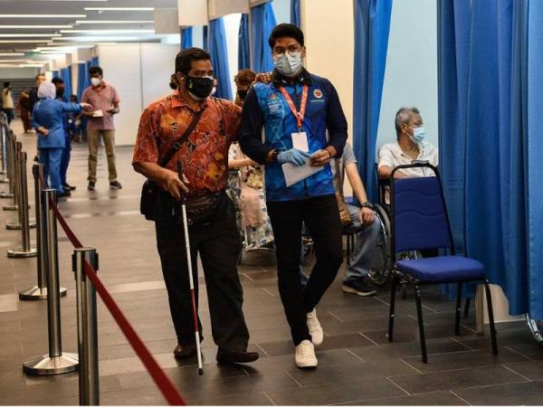 Penerima vaksin beratur menunggu giliran sambil dibantu beberapa sukarelawan untuk menerima suntikan vaksin Covid-19 di Pusat Pemberian Vaksin (PPV) Axiata Arena di Bukit Jalil. - Foto Bernama