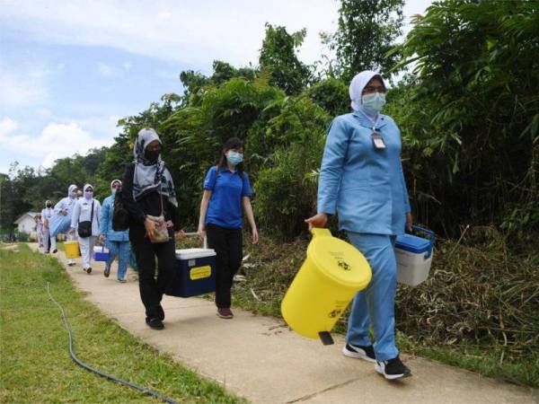 Petugas barisan hadapan Pusat Kesihatan Daerah (PKD) Jerantut mengangkat peralatan untuk vaksinasi selepas mengharungi sungai dengan menaiki bot untuk ke Kampung Orang Asli Sungai Kucing pada program Vaksinasi Masyarakat Orang Asli Ulu Tembeling, pada Rabu. - Foto Bernama