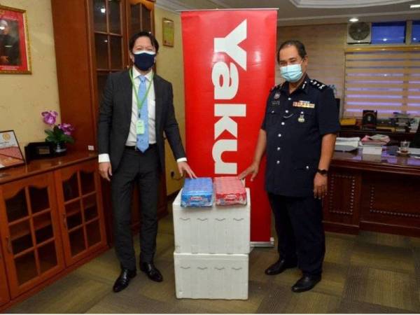 Abdullah (kanan) menerima sumbangan 500 botol air minuman probiotik Yakult daripada Hiroshi di Ibu Pejabat Polis Kontinjen (IPK) Kelantan pada Khamis.