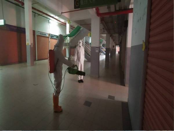 Dua pekerja melakukan kerja-kerja sanitasi Kompleks Pekan Rabu pada Jumaat.