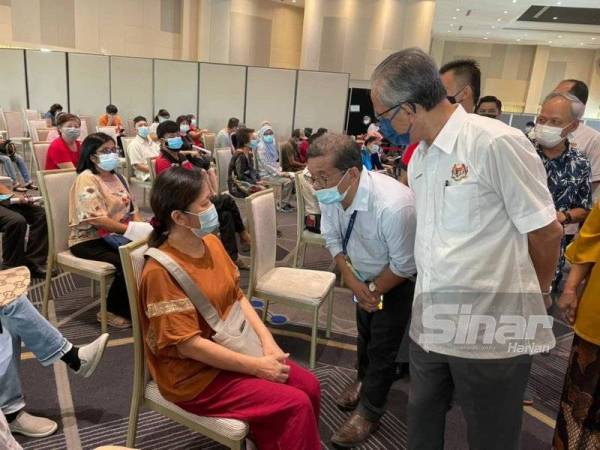 Datuk Kamarudin (kanan) beramah mesra dengan penerima vaksin.