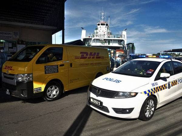 Anggota Polis Diraja Malaysia (PDRM) membuat kawalan keselamatan semasa ketibaan kenderaan DHL Express yang membawa sebanyak 3,020 dos bekalan vaksin Pfizer-BioNTech dengan menggunakan perkhidmatan pengangkutan laut feri kenderaan di Terminal Feri Antarabangsa Labuan ketika tinjauan hari ini.