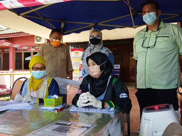 Mohd Khairil Anuar (belakang,kiri) dan Muhammad Ridzal (belakang, kanan) meninjau proses pendaftaran kehadiran penerima vaksin dalam kalangan penduduk sekitar kawasan Sungai Lembing di Klinik Kesihatan Sungai Lembing di sini pada Sabtu.