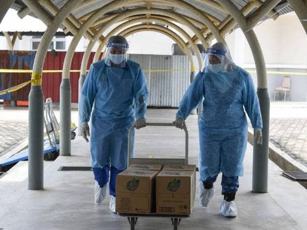 Tuan Mohd Khosim (kiri) bersama rakan setugasnya menghantar air minuman untuk diberikan kepada penghuni pusat kuarantin Covid-19 di IPG Kampus Dato’ Razali Ismail. - Foto Bernama