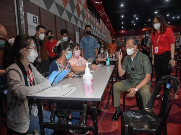 Muhyiddin (dua, kanan) beramah mesra bersama petugas kesihatan ketika meninjau proses vaksinasi di Pusat Pemberian Vaksin (PPV) Sunway Pyramid Convention Center (SPCC), pada Ahad. Turut sama Ketua PPV SPCC Angela Lee (kanan).- Foto Bernama
