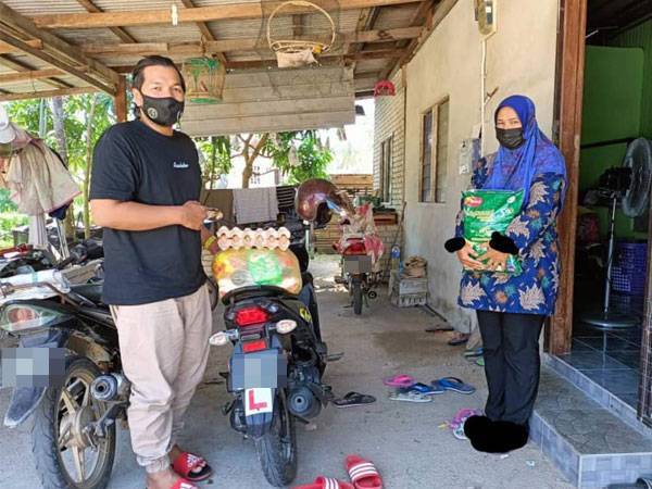 Muhammad Syariezal (kiri) menyampaikan sumbangan kepada sebuah keluarga yang terkesan akibat pandemik Covid-19. FOTO: Ihsan Fisabilillah Terengganu.