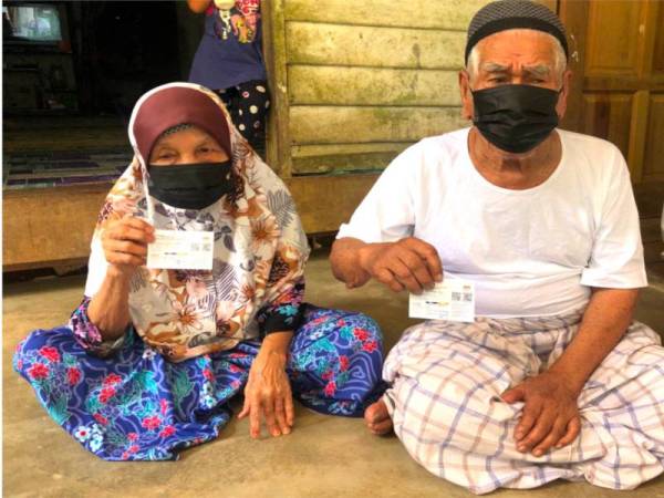 Mamat (kanan) dan Syarifah menunjukkan kad vaksin selepas melengkapkan dos kedua jenis Sinovac pada Ahad. - Foto Sinar Harian 