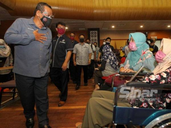 Aminuddin (kiri) bertanyakan sesuatu kepada penerima vaksin di PPV Mega di Dewan Tuanku Canselor USIM.
