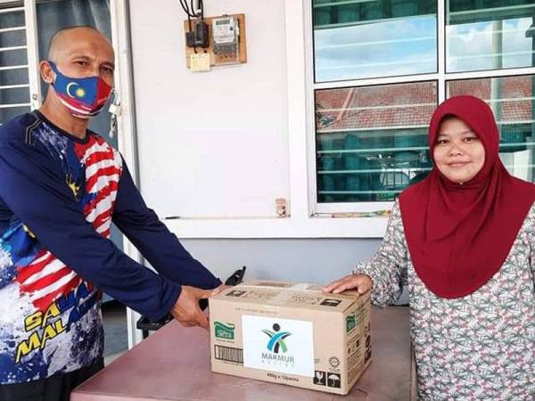 Ali Akbar (kiri) menghulurkan sumbangan selepas menyantuni keluarga Aishah di Lorong Tiram Jaya 5, Taman Tiram Jaya di sini pada Ahad.