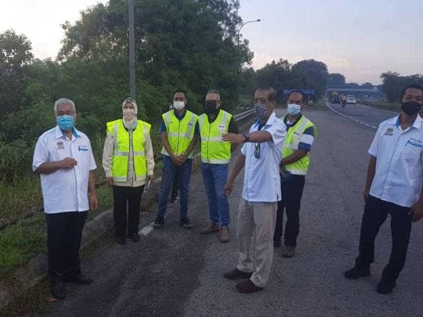 Hassan (kiri) meninjau keadaan jalan yang berlubang dan rosak di Lebuh Raya Pasir Gudang, Pasir Gudang.
