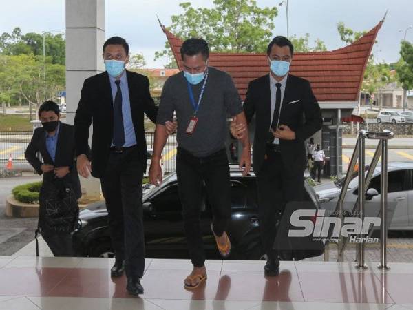 Tertuduh (tengah) diring SPRM di mahkamah.