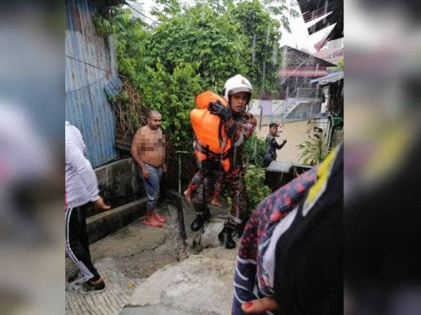 Anggota bomba menyelamatkan salah seorang kanak-kanak dalam kejadian banjir kilat pada pagi Selasa.