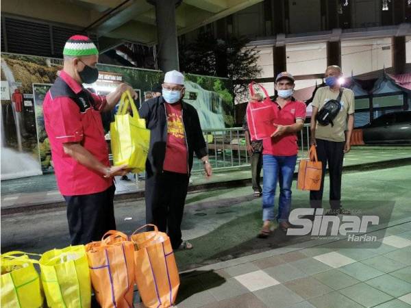 Tengku Khairul Idham (dua dari kiri) menyerahkan sumbangan kepada gelandangan di Hentian Bas MBKT di Kuala Terengganu pada Isnin.