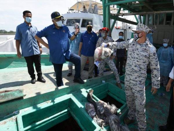 Hamzah (dua dari kiri) melihat hasil laut yang dirampas daripada bot nelayan ketika tinjauan operasi pematuhan SOP di Ibu Pejabat Maritim Terengganu di Kuala Terengganu pada Selasa. - Foto Bernama