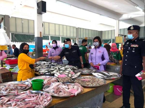 Abdul Rahim (tiga dari kiri) menyampaikan risalah Program Alert Norma Baharu oleh Amanita Skuad Aman Wanita (Amanita) kepada peniaga di Pasar Tok Guru, Pengkalan Chepa, Kota Bharu pada Selasa. - FOTO SINAR HARIAN