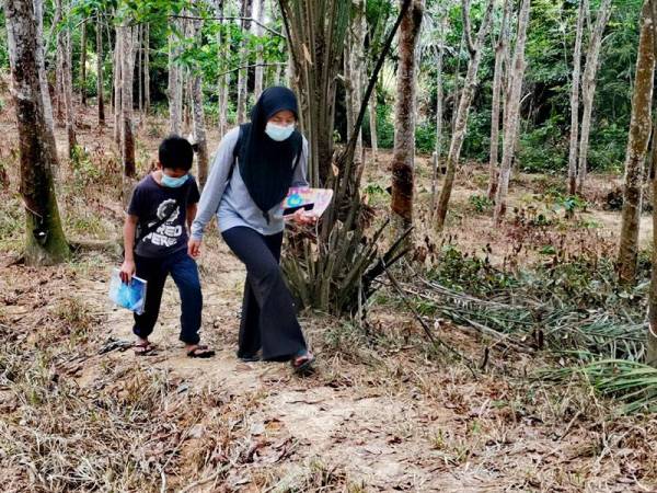 Mimi Ismaliza dan Mohamad Izman berjalan kaki selama lima minit untuk ke pondok kayu di kebun getah.
