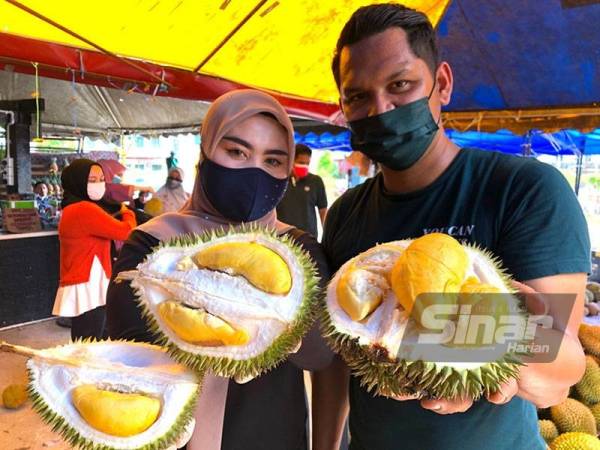 Shahmiazani (kanan) dan Shaidatul Fatini melelong durian bagi membantu rakyat terjejas pandemik Covid-19 tetap dapat menikmati buah durian yang dijual murah di gerai mereka di tepi jalan Kampung Semat Jal, Wakaf Bharu, Tumpat.