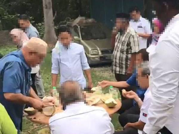 Rashid (duduk kanan) bersama-sama individu sedang makan durian dalam sebuah kebun durian dipercayai dalam daerah Batu Pahat.