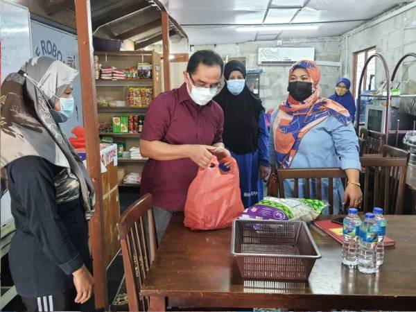 Baharuddin (tengah) membantu mengagihkan barang keperluan asas daripada Gerobok Prihatin kepada penduduk yang memerlukan di Rumah Pangsa Taman Air Biru, Pasir Gudang pada Rabu.