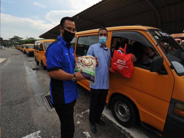 Sabarudin memberikan bantuan barangan keperluan asas kepada pemangu van sekolah dalam Program Bakul Prihatian Johor di pekarangan Sekolah Menengah Kota Masai 2, Pasir Gudang.