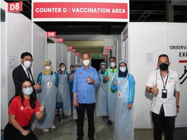 Wan Junaidi (tengah) bersama para pegawai bertugas Kementerian Kesihatan (KKM) pada lawatan kerja di Pusat Pemberian Vaksin (PPV) Pusat Dagangan Dunia (WTC), pada Khamis. - Foto Bernama 