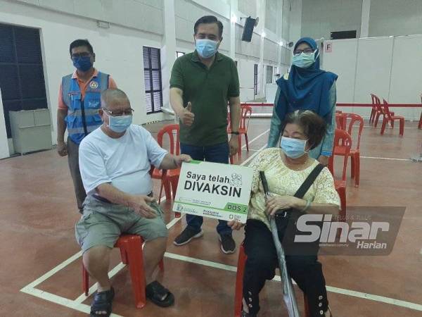Anthony (tengah) menunjukkan tanda bagus kepada warga emas yang menerima vaksin di PPV Sikamat pada Khamis.