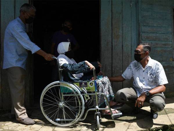 Rosol (kanan) beramah mesra dengan warga emas Tuan Sarifah Zaharah Syed Akil, 56, (tengah) selepas menyumbangkan kerusi roda di Kampung Merbau Pulas, Ajil hari ini.  -Foto Bernama