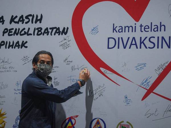 Khairy Jamaluddin menandatangani papan ‘kami telah divaksin’ selepas selesai lawatan kerja di Pusat Pemberian Vaksin (PPV) mega di Pusat Konvensyen dan Pameran Antarabangsa Mines (MIECC) pada Sabtu. - Foto Bernama 