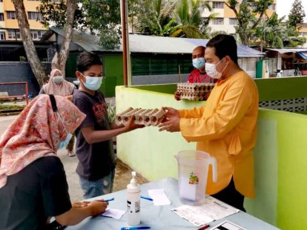 Md Fakarudin (kanan) menyerahkan sepapan telur kepada penduduk warga asing.