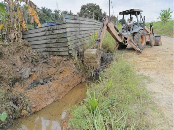 Jengkaut digunakan bagi menutup tumpahan sisa bahan kimia daripada tangki yang bocor dari mengalir keluar ke parit dan sungai yang berdekatan di stor penyimpan bahan tersebut di Kampung Baru Sengkang Kulai hari ini. Foto Bernama