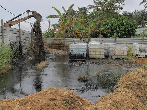 Jengkaut digunakan bagi menutup tumpahan sisa bahan kimia daripada tangki yang bocor dari mengalir keluar ke parit dan sungai yang berdekatan di stor penyimpan bahan tersebut di Kampung Baru Sengkang Kulai hari ini. - Foto Bernama
